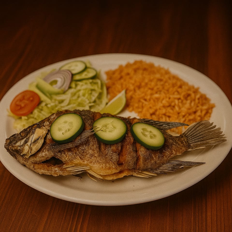 Whole fried fish garnished with cucumber slices, served with Mexican rice, lettuce salad, tomato, onion, and lime.