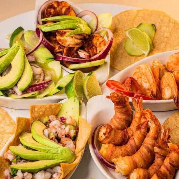 A platter of various shrimp dishes, including ceviche, bacon-wrapped shrimp, and shrimp with peppers.